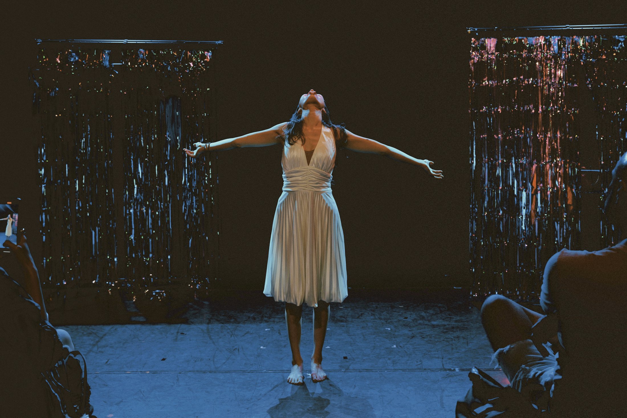 Feride Morçay standing barefoot with her arms open between the audience